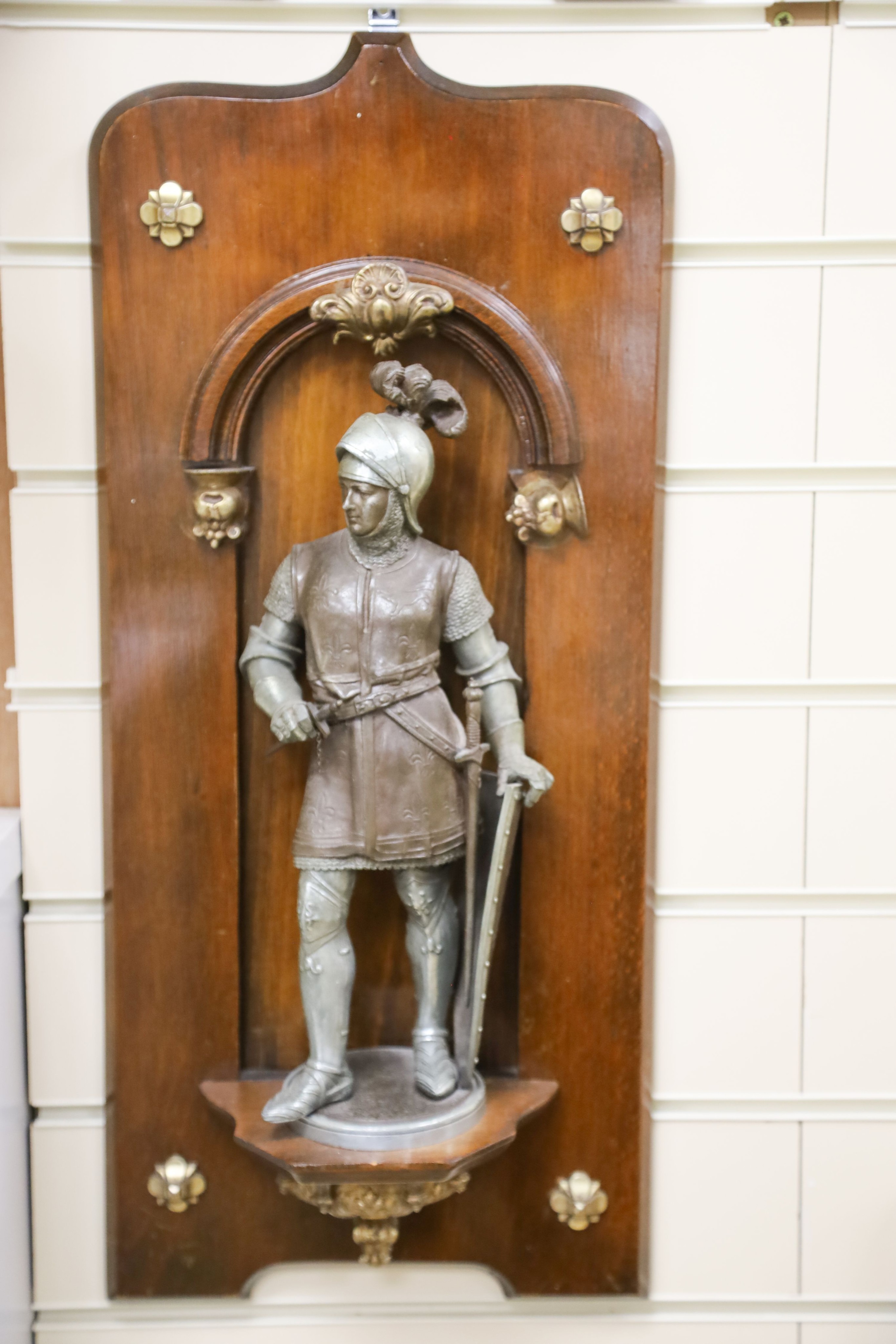 A pair of cast spelter figures of a medieval knight and a cavalier, each mounted on a mahogany niche